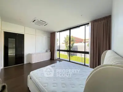 Spacious bedroom with large windows and modern design in a bright, airy apartment.