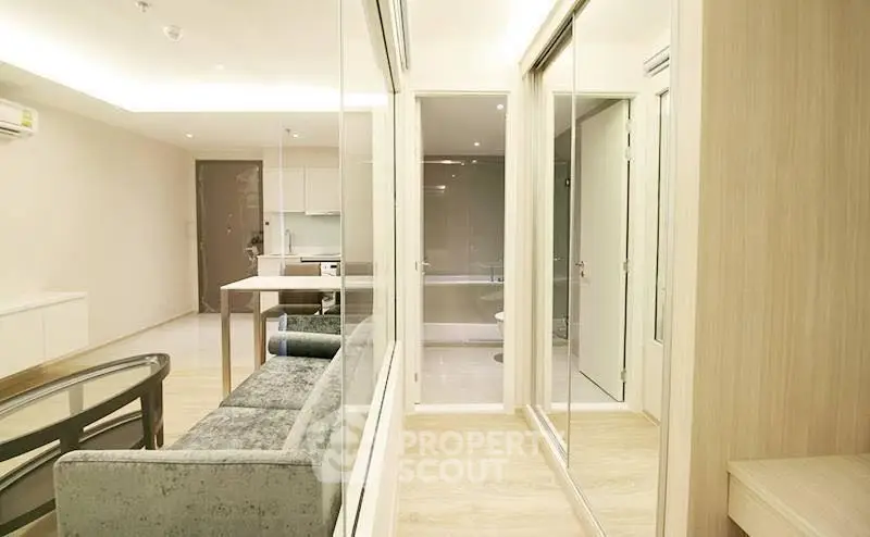 Modern open-plan living room with sleek furniture and glass partitions in a stylish apartment.