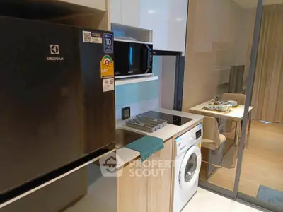 Modern kitchen with Electrolux fridge, microwave, and washing machine in compact layout.