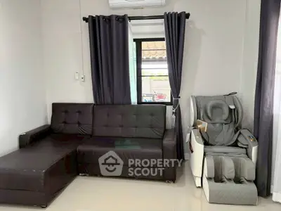 Modern living room with black leather sofa and massage chair, featuring sleek curtains and polished floors.