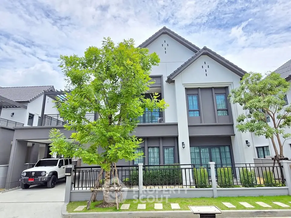Stunning modern two-story house with lush greenery and spacious driveway.