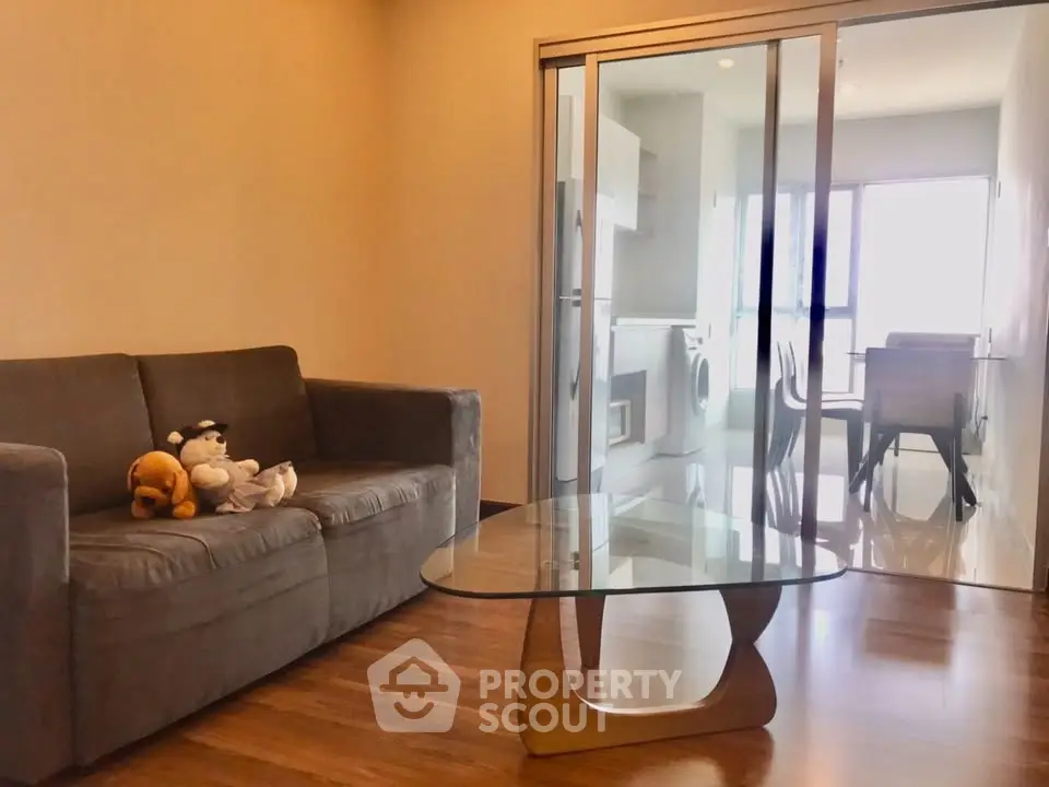 Modern living room with glass table and plush sofa in open layout apartment.