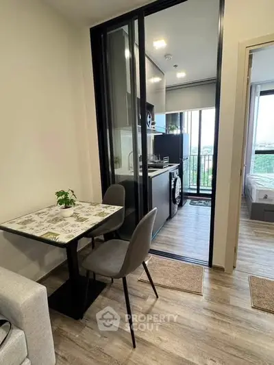 Modern apartment interior with open kitchen and dining area, featuring sleek design and natural light.