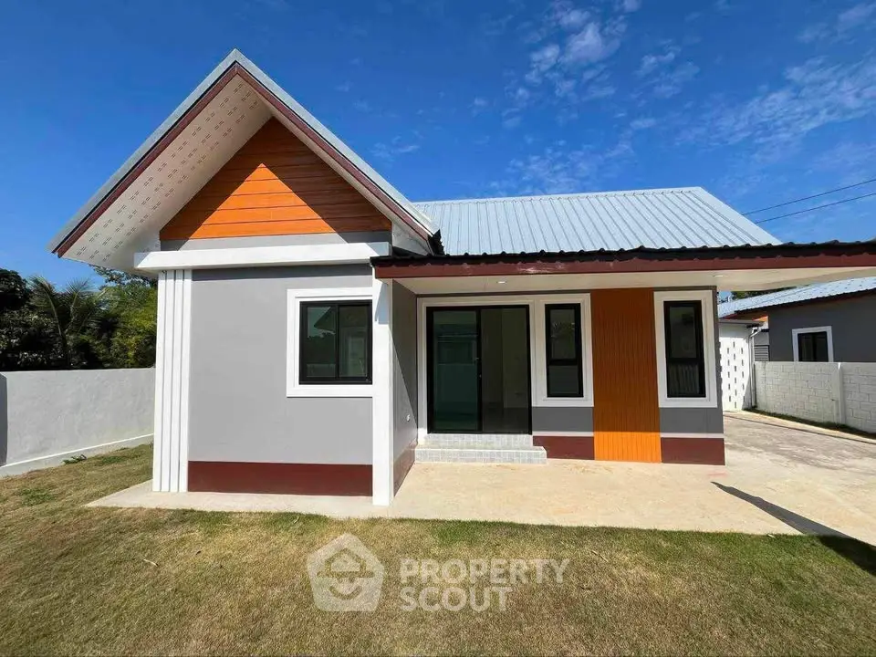 Charming modern single-story house with vibrant orange accents and spacious driveway.