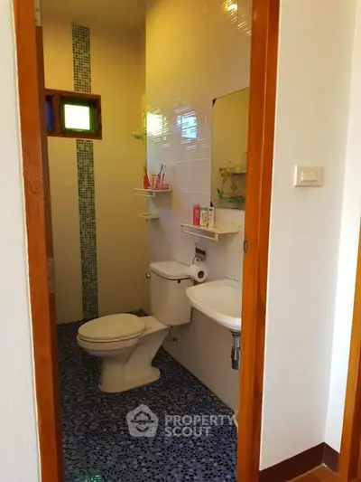 Compact bathroom with modern fixtures and colorful tile flooring, ideal for small spaces.