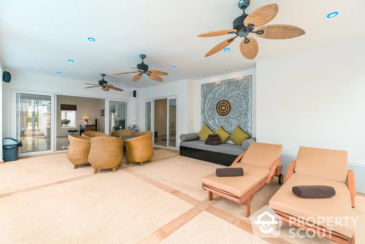 Spacious living room with tropical ceiling fans, plush seating, and abundant natural light, perfect for relaxation and entertaining guests.