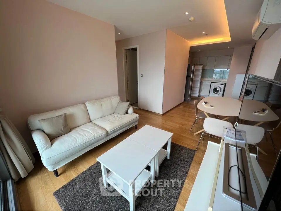 Modern living room with open kitchen, featuring cozy sofa and dining area, perfect for urban living.