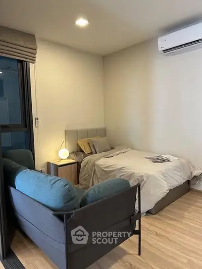 Cozy bedroom with modern decor and air conditioning, featuring a comfortable bed and stylish seating area.