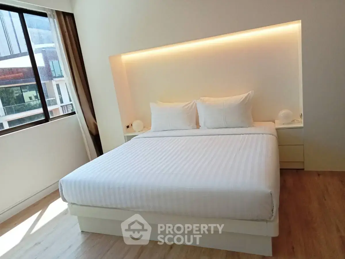 Spacious bedroom with modern design and large window offering natural light.