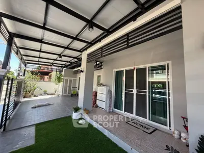 Modern covered patio with sliding glass doors and green artificial turf.