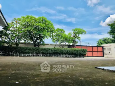 Spacious outdoor area with lush greenery and clear blue sky, perfect for relaxation and gatherings.