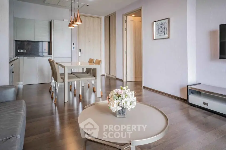 Modern open-plan living room with sleek kitchen and stylish dining area, featuring elegant decor and natural light.