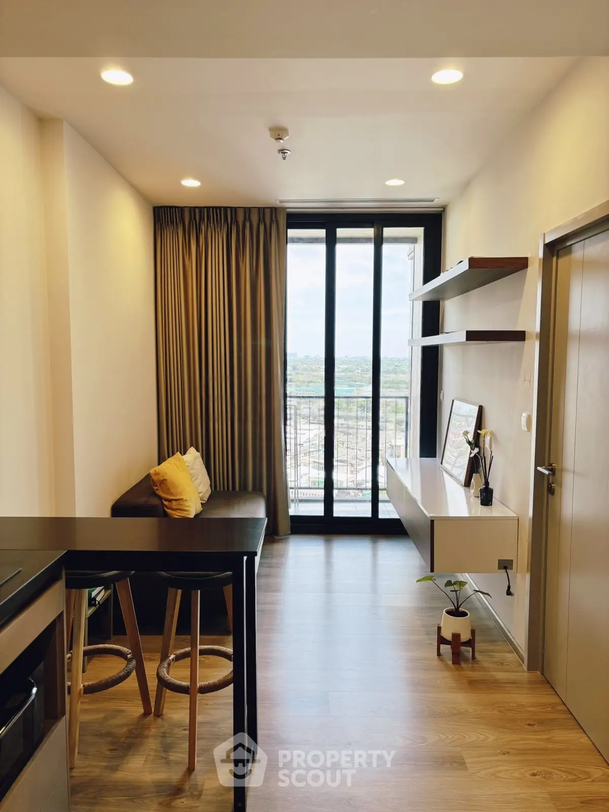 Modern living room with balcony view, sleek furniture, and stylish decor in a high-rise apartment.
