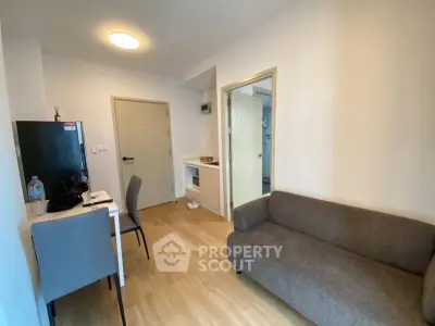 Cozy living room with modern furniture and wooden flooring in a compact apartment.