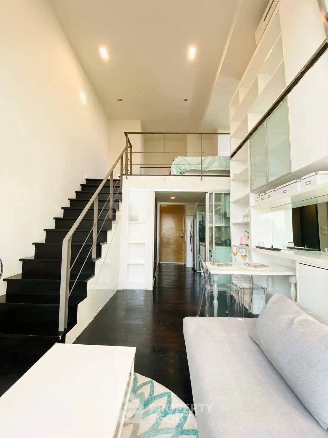 Modern loft apartment with mezzanine, sleek black staircase, and open kitchen layout.