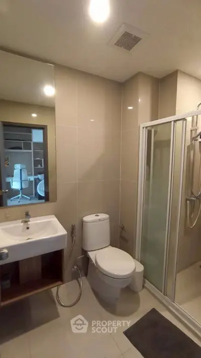 Modern bathroom with glass shower and sleek fixtures in contemporary apartment.