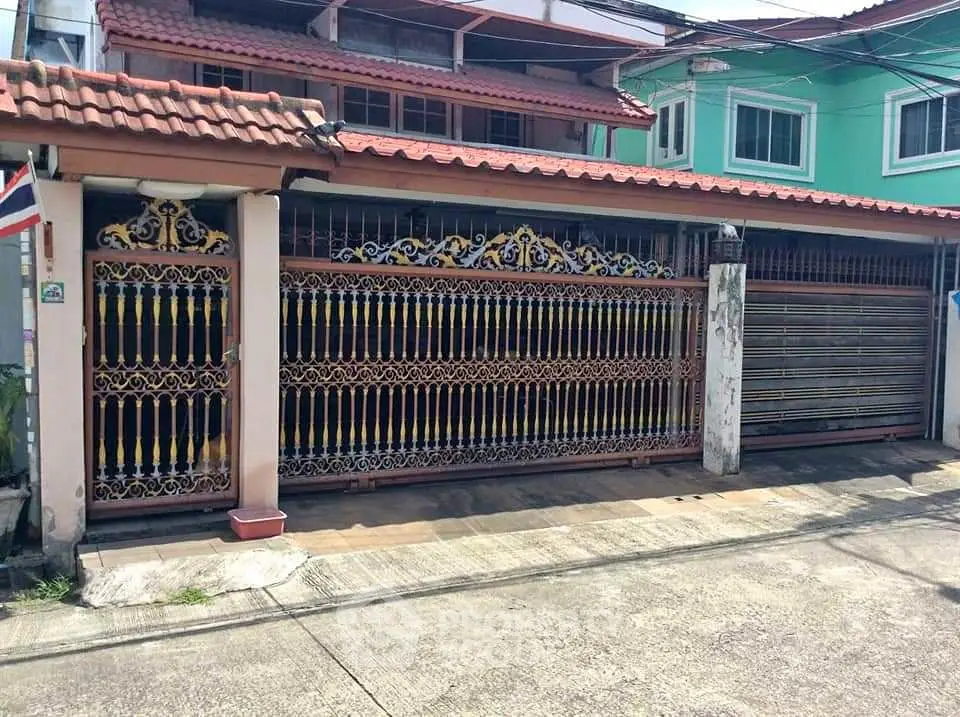 Charming residential property with ornate gate and tiled roof in a suburban neighborhood.