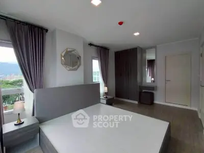 Spacious modern bedroom with large windows and stylish decor in a high-rise apartment.