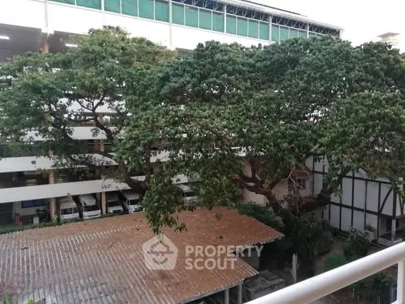 Spacious outdoor view with lush trees and adjacent building, ideal for nature lovers.