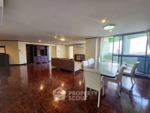 Spacious open-plan living room with elegant wooden flooring and large windows offering stunning views.