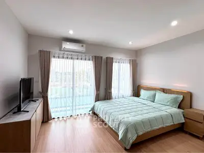 Spacious bedroom with large windows and modern furnishings in a bright, airy setting.
