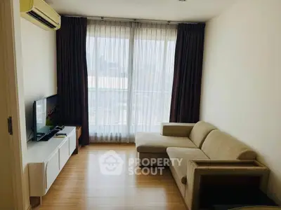 Modern living room with large windows, cozy sofa, and sleek TV setup in a bright apartment.