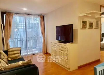 Cozy living room with large TV and elegant decor, featuring a comfortable sofa and natural light.