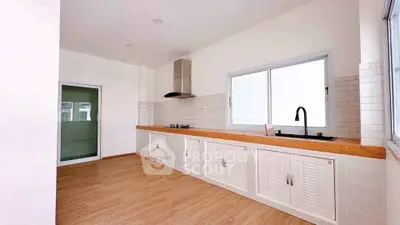 Spacious kitchen with modern fixtures and wooden flooring, featuring a sleek gas stove and ample storage.