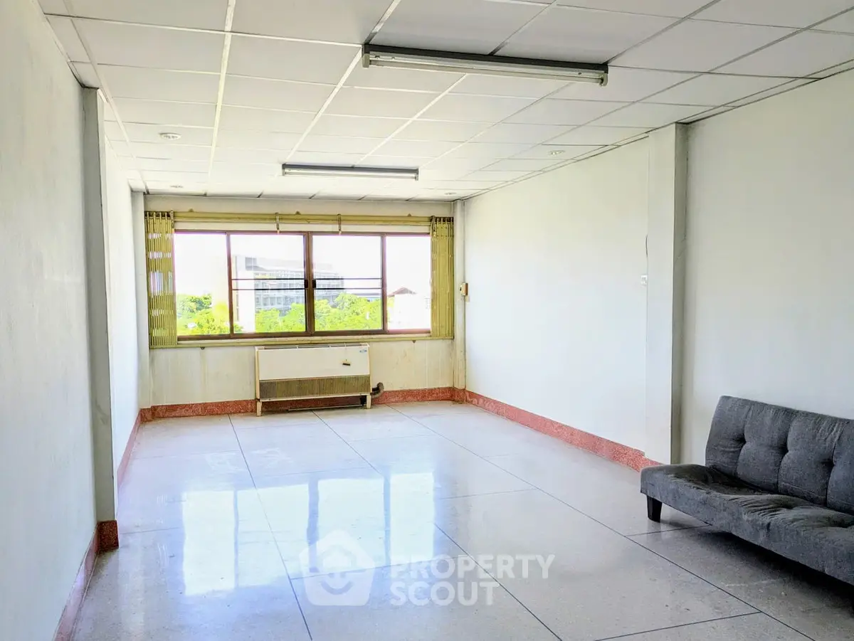 Spacious unfurnished room with large window and natural light, ideal for customization.