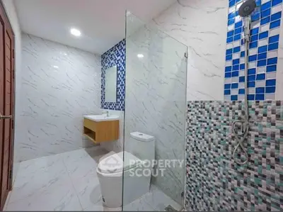 Modern bathroom with glass shower, mosaic tiles, and sleek fixtures.