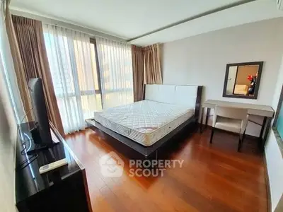Spacious bedroom with large windows and hardwood floors in modern apartment.