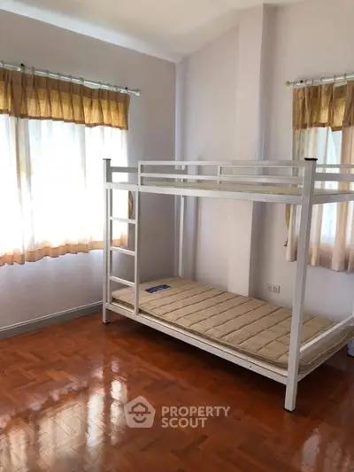 Spacious bedroom with bunk bed and natural light, perfect for family living.