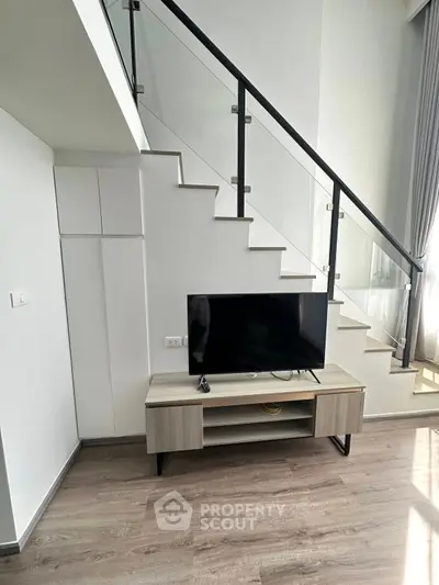 Modern living room with stylish staircase and TV setup, perfect for contemporary urban living.