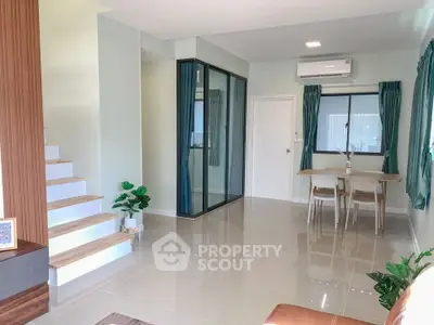 Modern living room with dining area and staircase, featuring sleek design and natural light.