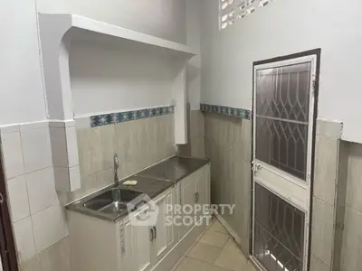 Compact kitchen with stainless steel sink and tiled backsplash