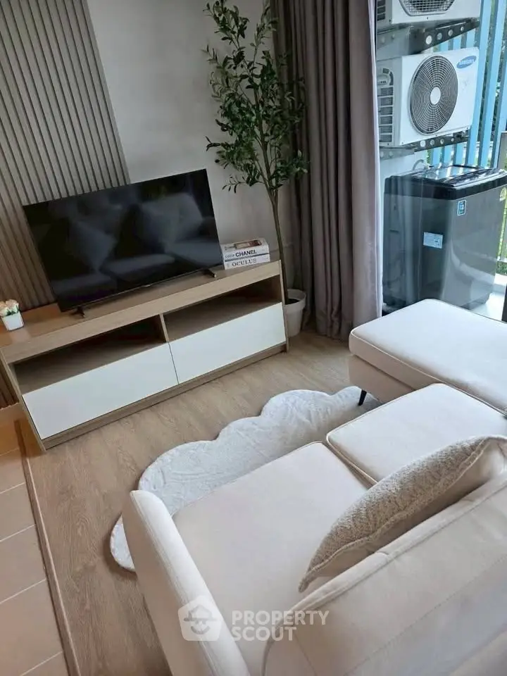 Modern living room with TV, cozy sofa, and balcony view