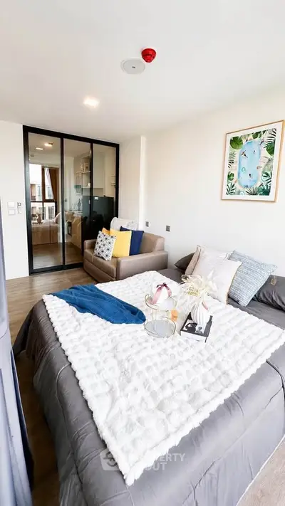 Modern bedroom with cozy decor and glass sliding doors leading to a stylish living area.
