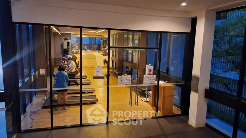 Modern gym with glass walls and fitness equipment in upscale residential building.