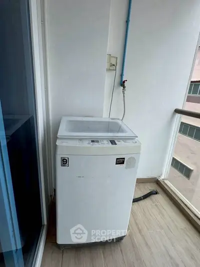 Compact washing machine on a balcony with city view, ideal for urban living.