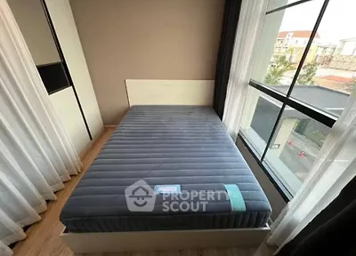 Cozy bedroom with large window and modern bed in a bright, airy space.