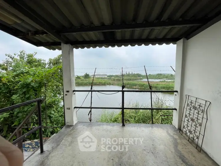 Charming balcony with serene river view and lush greenery, perfect for relaxation.