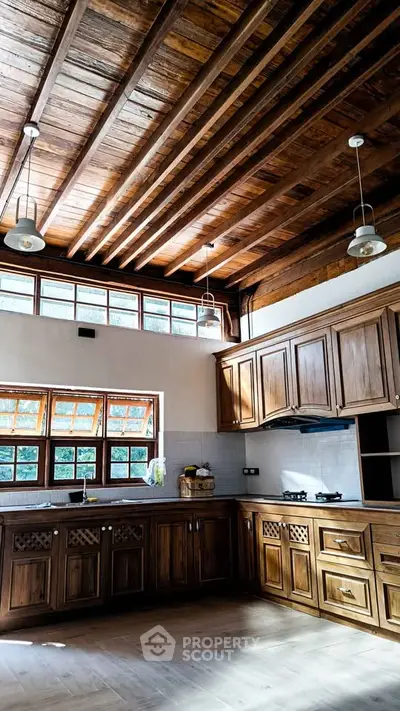 Spacious kitchen with wooden cabinets and high ceiling, featuring natural light and modern gas stove.