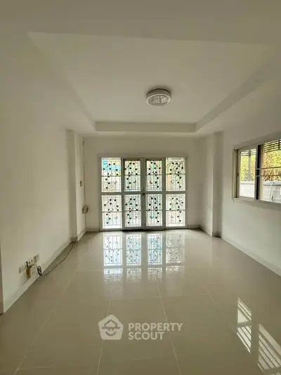 Spacious empty room with large windows and tiled floor, perfect for customization.