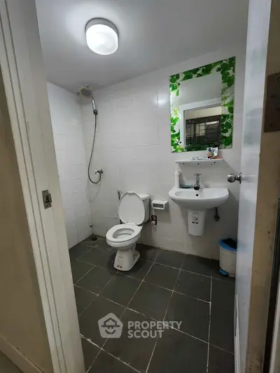 Modern bathroom with shower, toilet, and sink in a sleek white-tiled design.