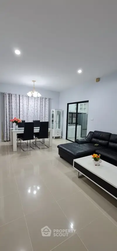 Spacious modern living room with sleek black leather sofa and elegant dining area.