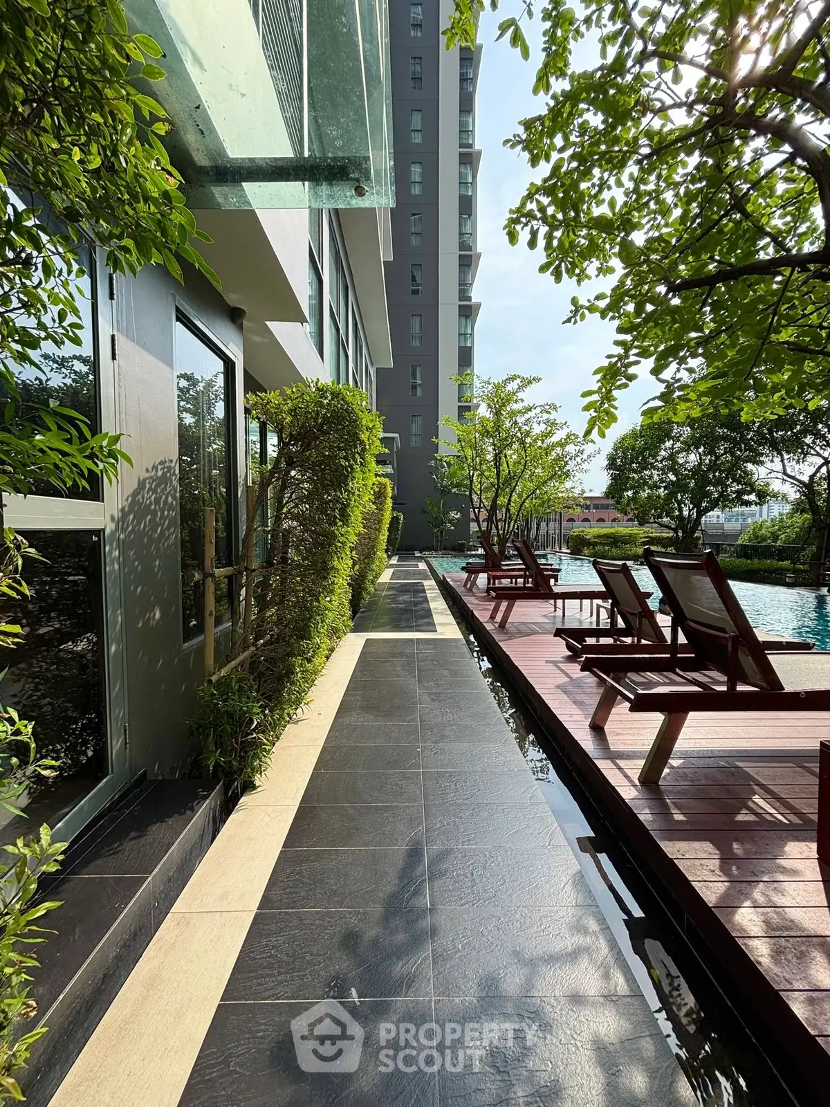 Luxurious poolside area with sun loungers and lush greenery in a modern residential complex.