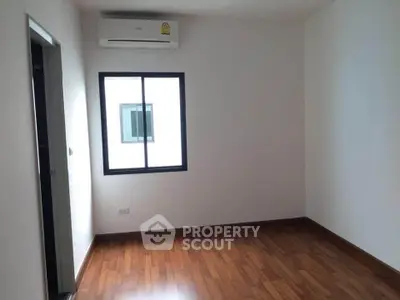 Spacious empty room with wooden flooring and air conditioning, perfect for customization.