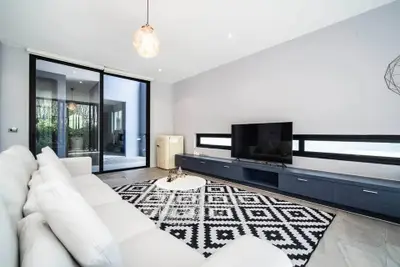 Modern living room with sleek design and large TV, featuring stylish decor and ample natural light.