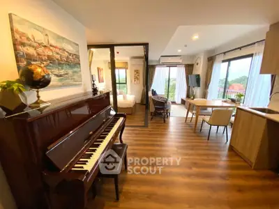 Spacious open-plan living room with piano and dining area, featuring large windows and modern decor.