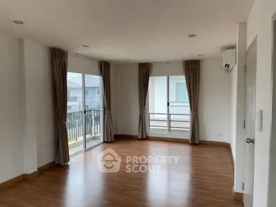 Spacious empty living room with wooden flooring and large windows